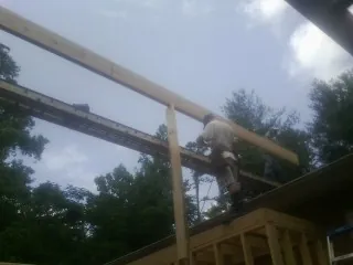 Carpenter setting a ridge beam over a new addition frame — Ice Dam Removal by Roofing Brothers in Westborough