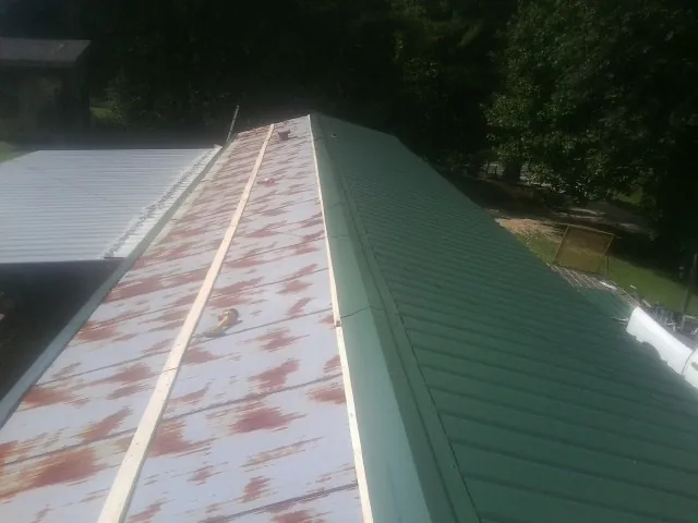 Old rusted panels beside newly installed green metal roofing — Wind Damage Roof Repair by Roofing Brothers in Westborough