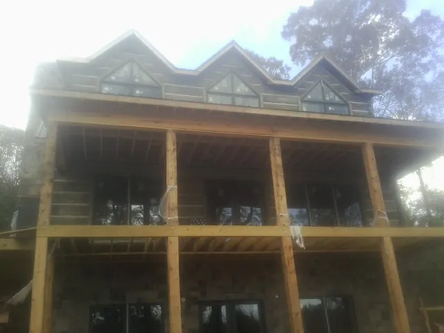 Dormers and porch framing on a large log home under construction — Roof Coating work by our crew in Westborough