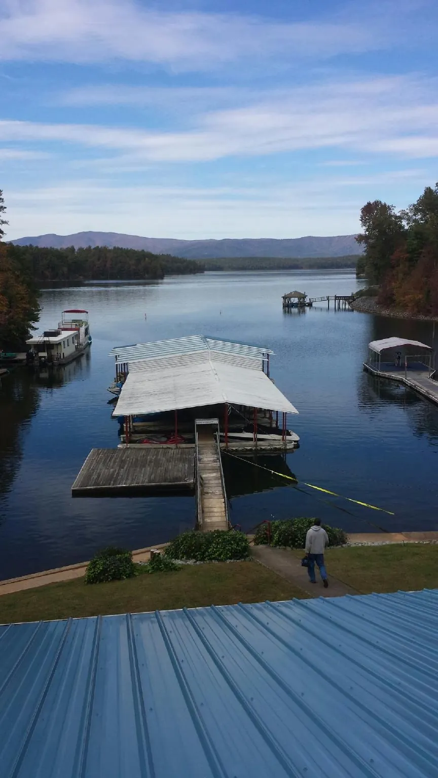 View across a lake from a newly installed blue metal roof in Westborough