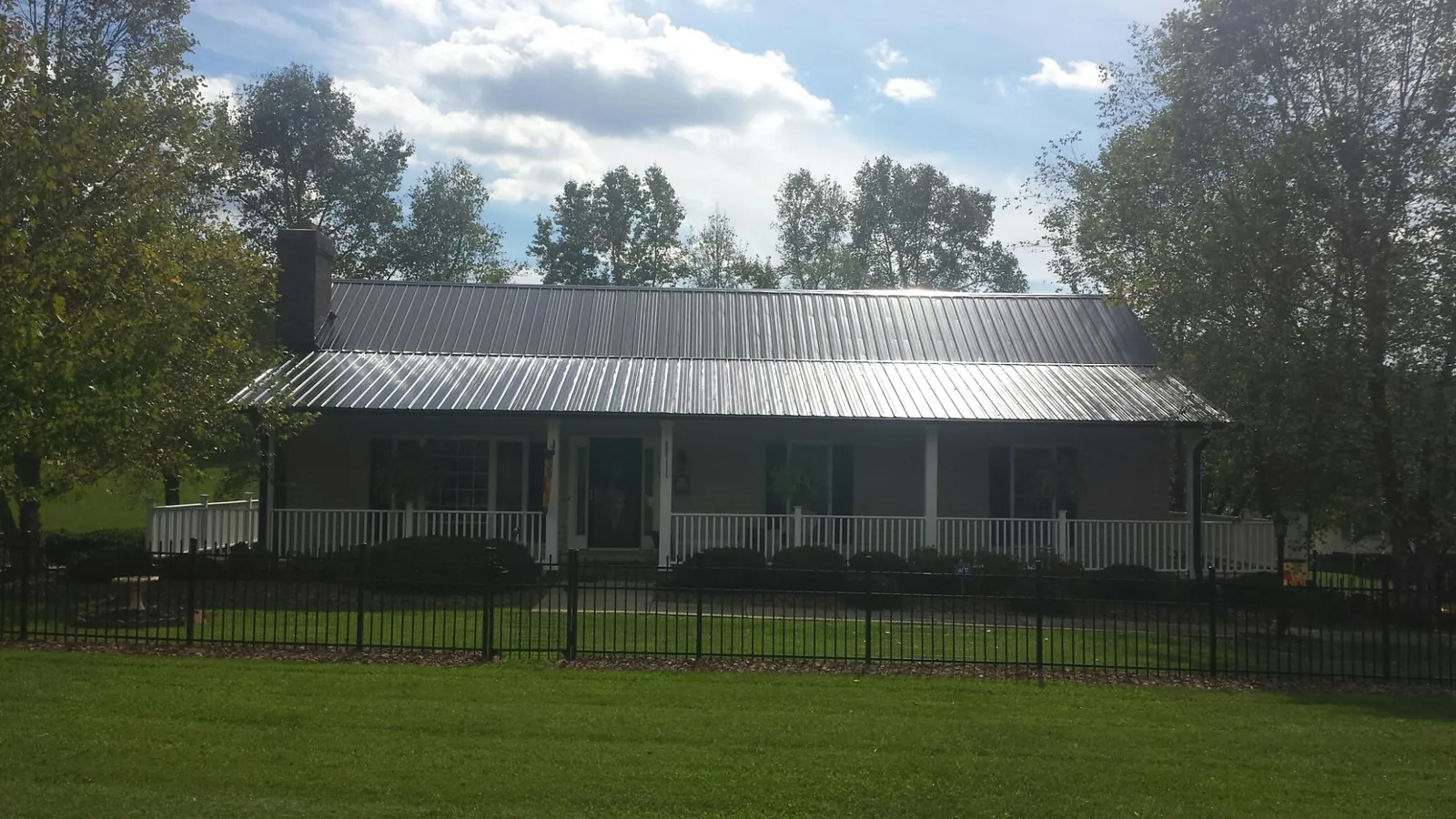 Gray metal roof on a brick ranch with a full width front porch — Gutter Guard Installation work by our crew in Westborough