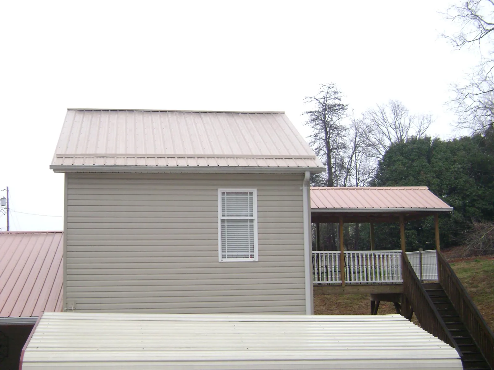 Tan metal roofs on a two story addition and attached porch, from a Roof Replacement job in Westborough